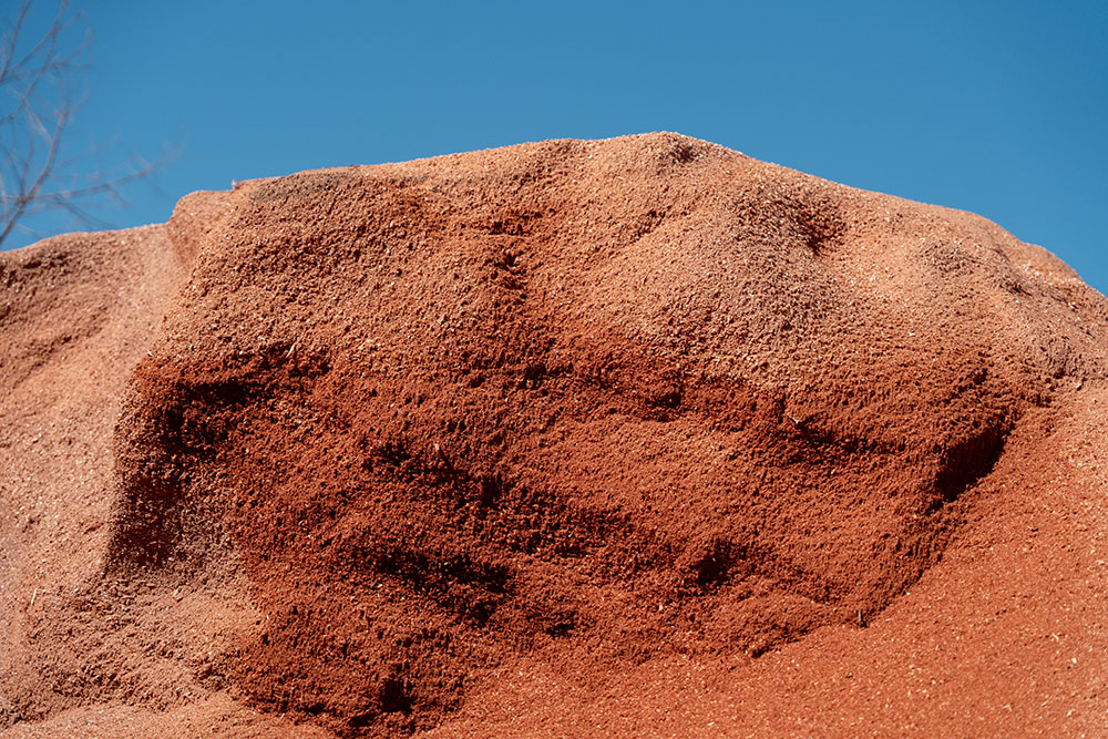 Cedar mulch pile against a clear blue sky, emphasizing its natural texture and color, relevant to Eastern Red Cedar's use in home decor and safety for pets and children.