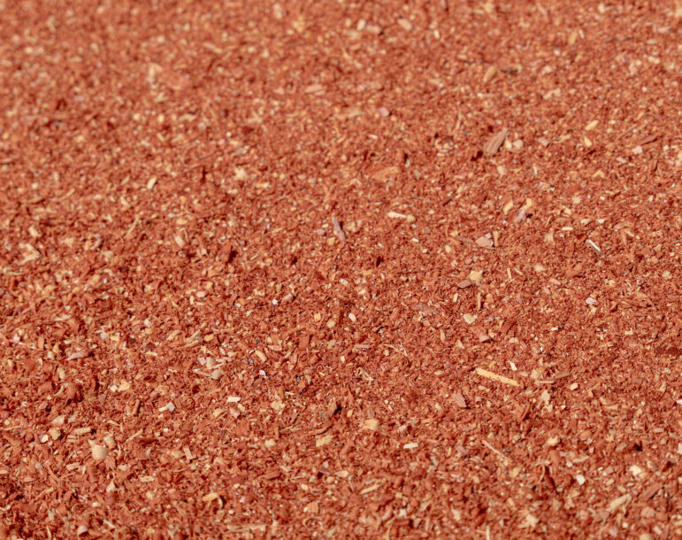 Aromatic red cedar mulch, finely shredded wood chips, showcasing rich color and texture, ideal for landscaping and gardening applications.