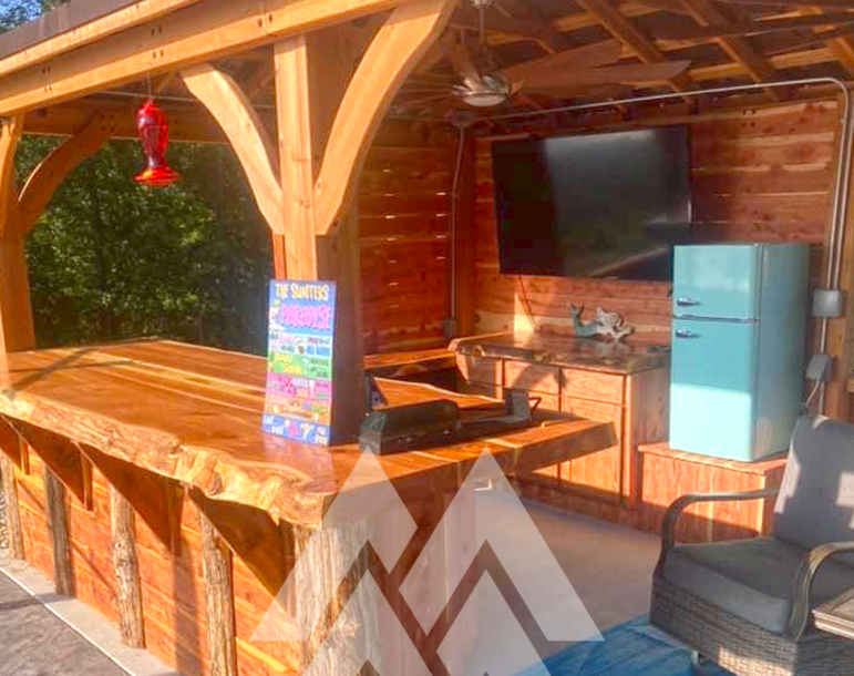 Outdoor cedar bar and kitchen with live-edge countertops, cedar walls, and exposed beam framing under a covered patio structure